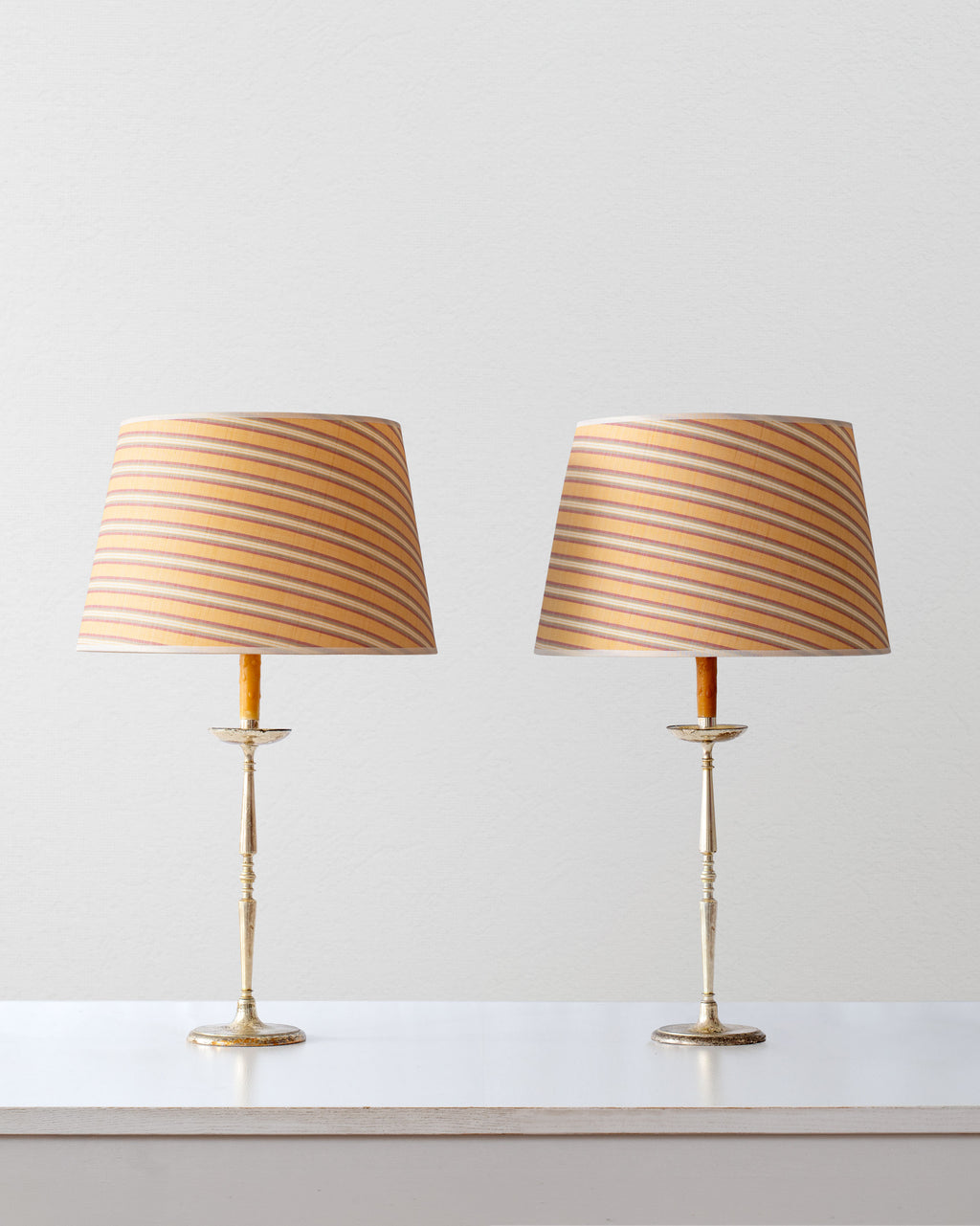 Two table lamps with striped shades on a white surface and light gray background