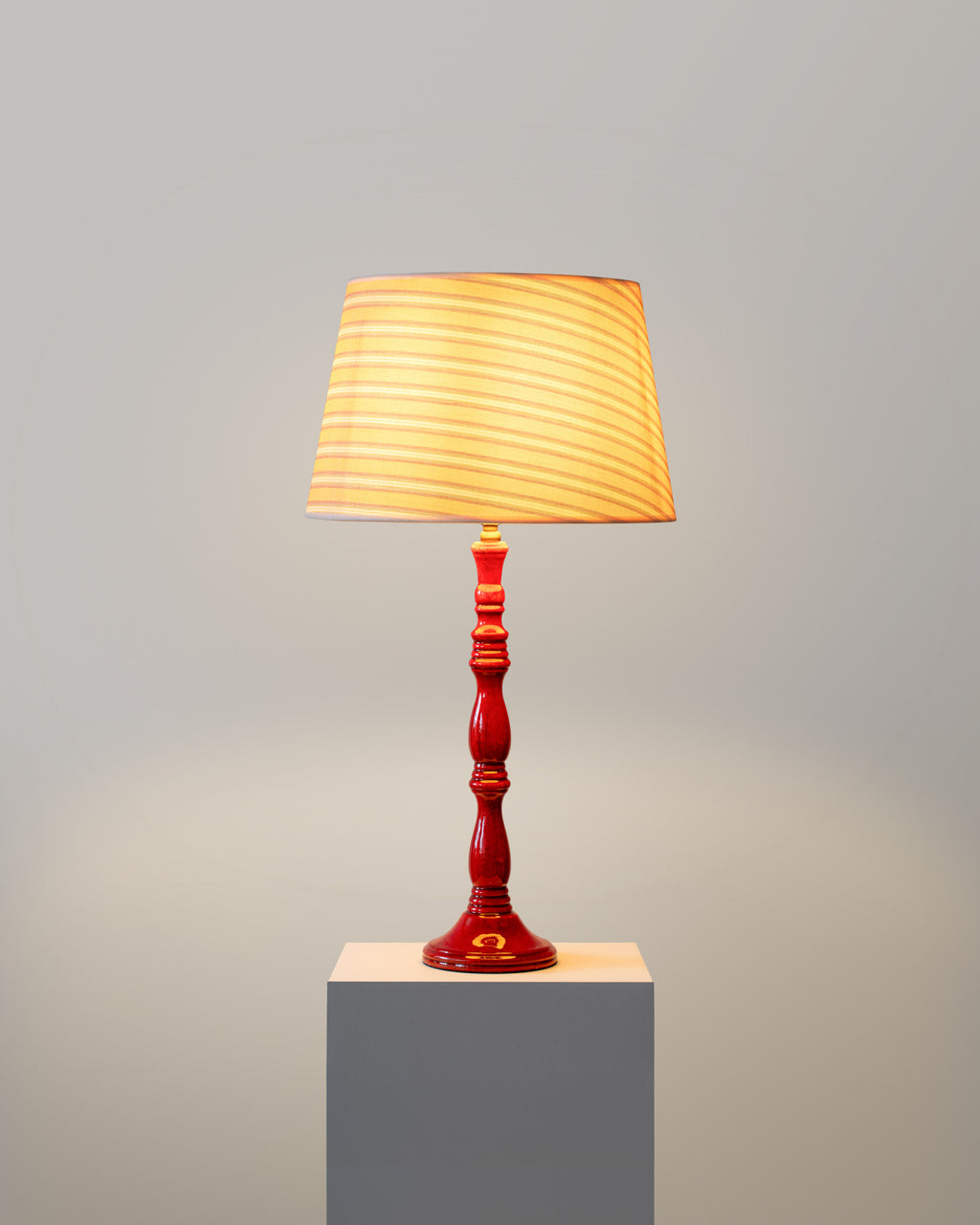 Table lamp with a red base and yellow shade on a gray background