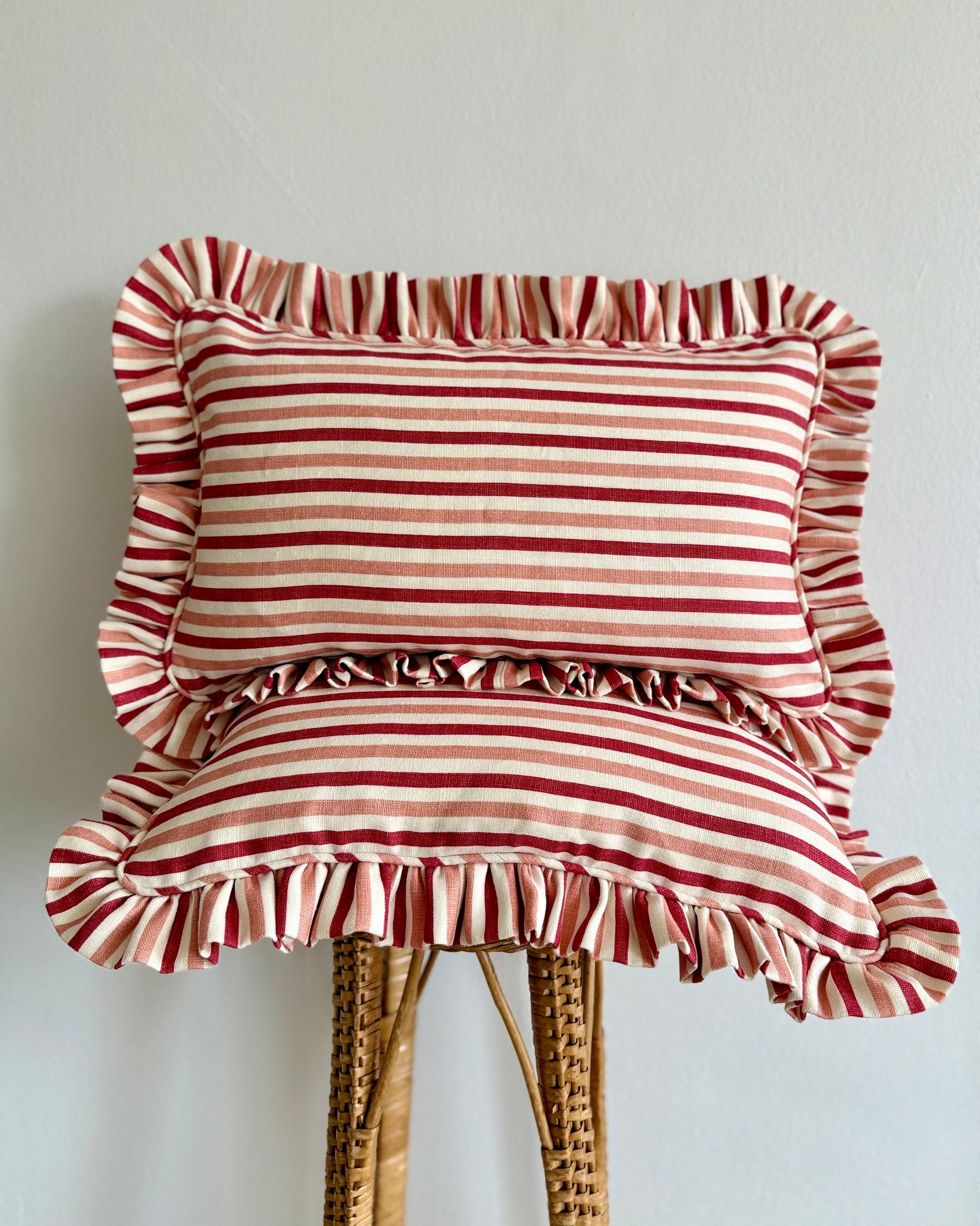 Pink and white striped cushion with ruffles on a wooden stool