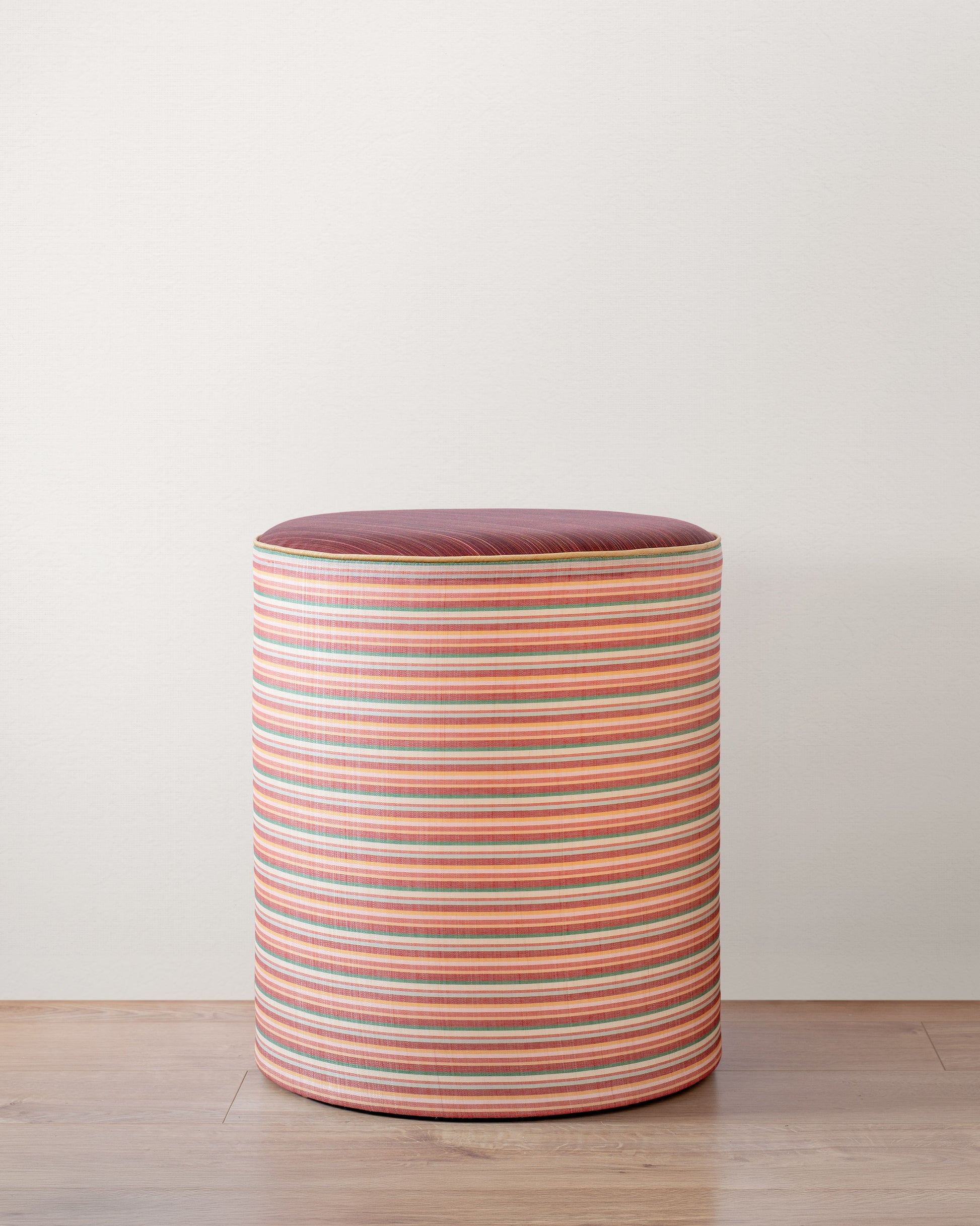 Striped cylindrical stool on a wooden floor with a white background