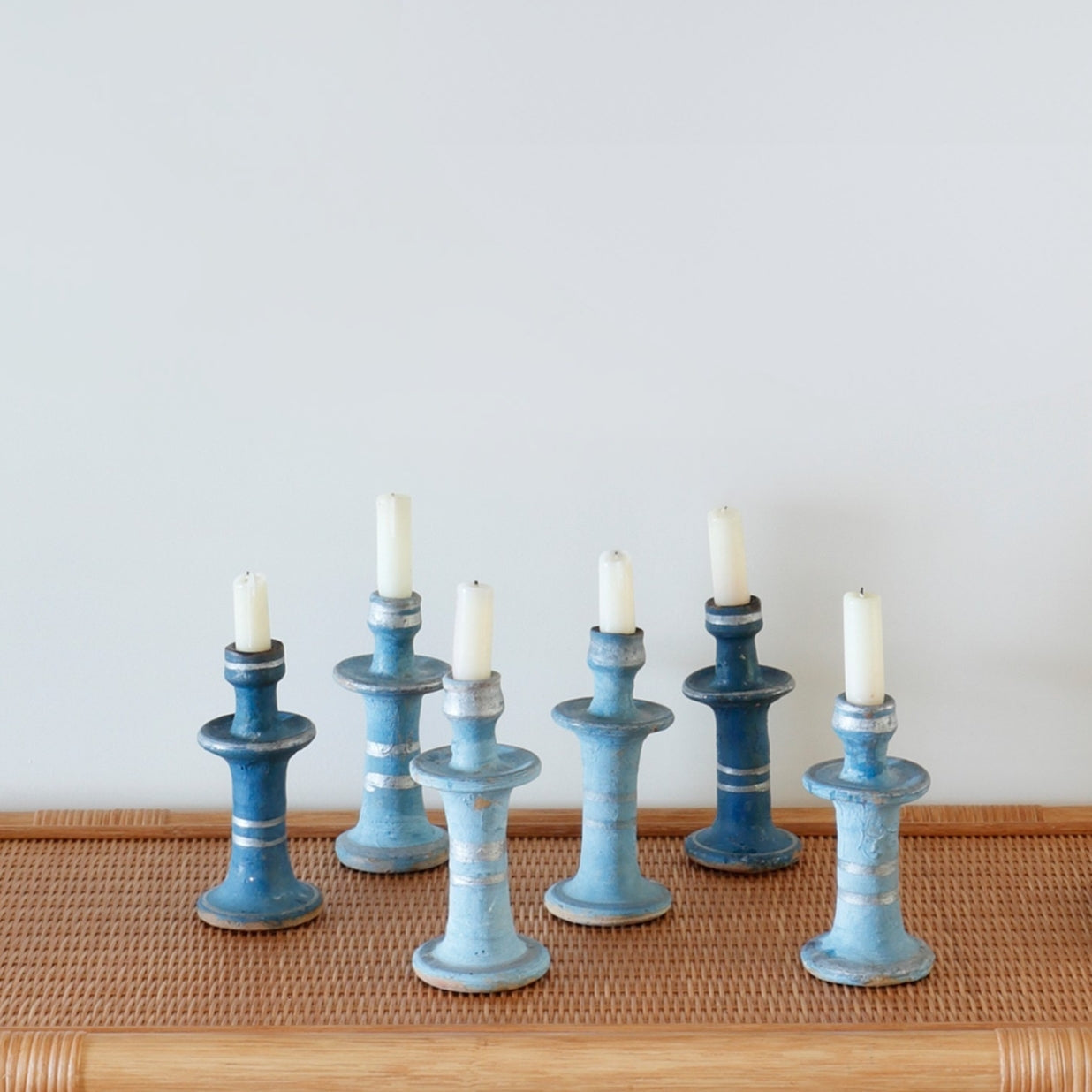Set of blue candle holders with candles on a wooden surface and light background